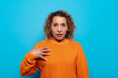 Orta yaşlı kadın şaşkın, şaşkın ve şaşırmış hissediyor, elleri göğsünde ve ağzı açık, kim olduğunu söylüyor, ben mi??