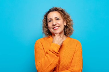 Orta yaşlı kadın gülümsüyor, hayattan zevk alıyor, mutlu, arkadaş canlısı, tatmin olmuş ve tasasız.