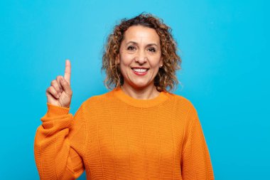 Orta yaşlı kadın mutlu bir şekilde gülümsüyor, tek eliyle boşluğu dolduruyor.