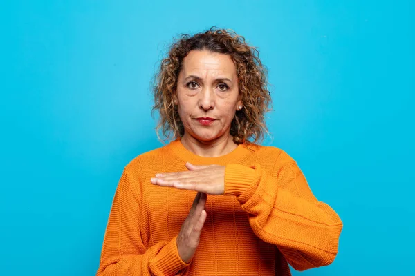 Orta yaşlı bir kadın ciddi, sert, kızgın ve canı sıkkın görünüyor.