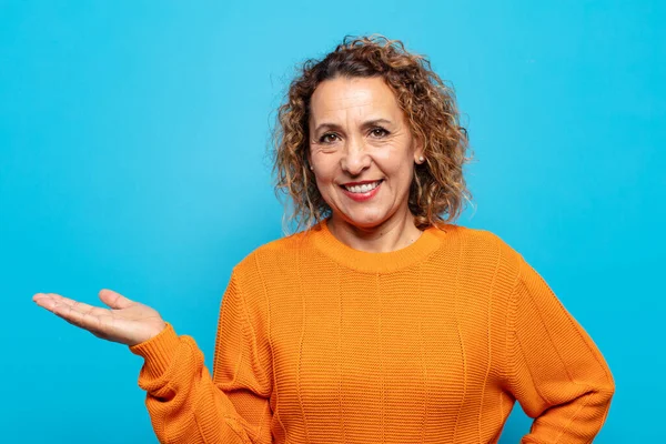 Orta yaşlı kadın gülümsüyor, kendinden emin, başarılı ve mutlu hissediyor, fotokopi alanında fikir veya konsept gösteriyor.