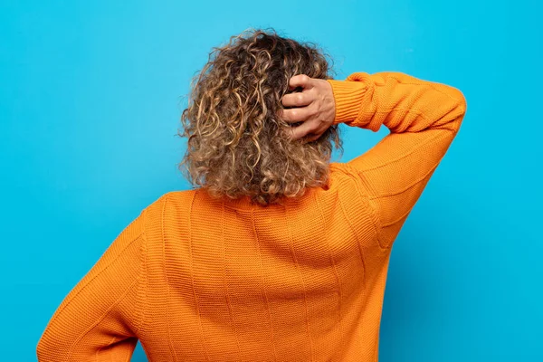 Orta yaşlı kadın düşünüyor ya da şüphe ediyor, kafasını kaşıyor, şaşkın ve kafası karışık hissediyor, geriye ya da arkaya bakıyor.