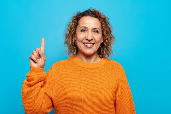 Orta yaşlı kadın mutlu bir şekilde gülümsüyor, tek eliyle boşluğu dolduruyor.