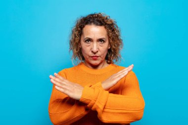 Orta yaşlı bir kadın senin tavırlarından rahatsız ve bıkkın görünüyor. Yeter artık! Eller önde çapraz, durmanı söylüyor.