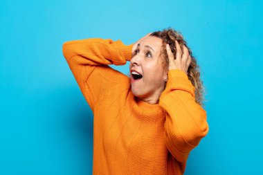 Orta yaşlı, ağzı açık bir kadın korkunç ve şok olmuş görünüyor. Korkunç bir hata yüzünden, el ele tutuşuyor.