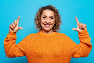 Orta yaşlı bir kadın iki eliyle kendi gülüşünü çiziyor, olumlu ve mutlu görünüyor, sağIık kavramı