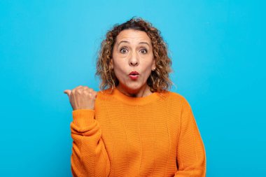 Orta yaşlı kadın inançsızlıktan şaşkın şaşkın bakıyor, yan taraftaki objeyi işaret ediyor ve diyor ki: