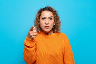 Orta yaşlı bir kadın kızgın agresif bir ifadeyle kameraya bakıyor. Öfkeli, deli bir patron gibi görünüyor.