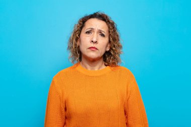 Orta yaşlı bir kadın üzgün ve mızmızlanıyor, mutsuz bir bakışla, negatif ve hayal kırıklığına uğramış bir tavırla ağlıyor.