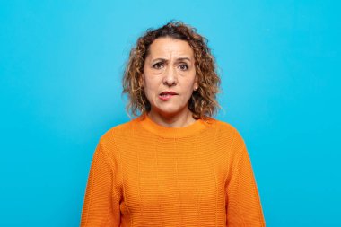 Orta yaşlı kadın şaşkın ve şaşkın görünüyor. Sinirli bir hareketle dudağını ısırıyor. Sorunun cevabını bilmiyor.