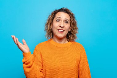 Orta yaşlı bir kadın mutlu, şaşırmış ve neşeli, pozitif bir tavırla gülümsüyor, bir çözüm ya da fikir buluyor.