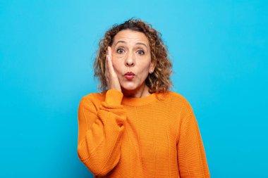 Orta yaşlı bir kadın ağzı açık bir şekilde yüz yüze inanmayarak şok olmuş ve hayrete düşmüş hissediyor.