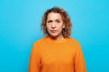 Orta yaşlı bir kadın kafası karışık ve kuşkulu, merak ediyor ya da karar vermeye çalışıyor.