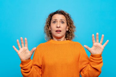 Orta yaşlı bir kadın sersemlemiş ve korkmuş hissediyor. Korkutucu bir şeyden korkuyor. Elleri açık ve uzak durun diyor.