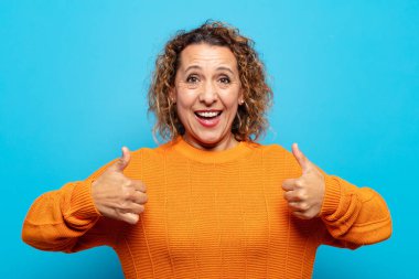 Orta yaşlı kadın mutlu, pozitif, kendine güvenen ve başarılı bir şekilde gülümsüyor.