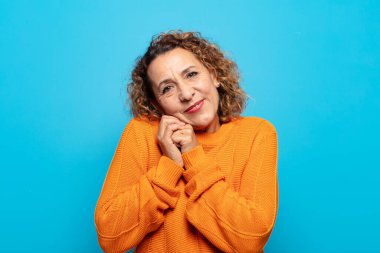 Orta yaşlı bir kadın aşık ve sevimli görünüyor. Sevimli ve mutlu. Romantik bir şekilde gülümsüyor.