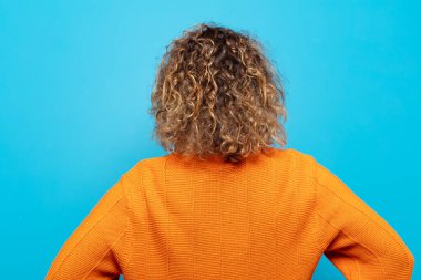 Orta yaşlı bir kadın kafası karışık ya da dolgun ya da şüphe ve soru dolu, merak ediyor, elleri kalçasında, dikiz aynasından.