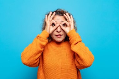 Orta yaşlı kadın şaşkın, şaşırmış ve şaşırmış hissediyor, elinde şaşkın, inançsız bir bakışla gözlük tutuyor.