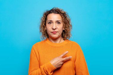 Orta yaşlı bir kadın mutlu, pozitif ve başarılı hissediyor, göğsünde el yapımı V ile, zafer ya da barış gösteriyor.