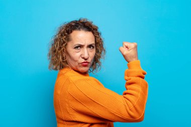 Orta yaşlı bir kadın kendini mutlu, tatmin olmuş ve güçlü hissediyor, kaslı ve formda, spor salonundan sonra güçlü görünüyor.