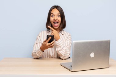 İspanyol kadın heyecanlı ve şaşırmış görünüyor. Yana ve yukarı doğru uzayı gösteriyor.