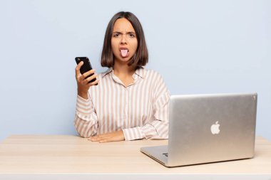 İspanyol kadın tiksinmiş ve rahatsız olmuş hissediyor, dilini dışarı çıkarıyor, iğrenç ve iğrenç bir şeyden hoşlanmıyor.