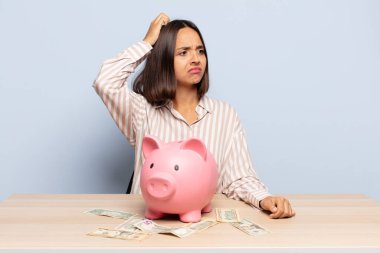 İspanyol kadın şaşkın ve şaşkın hissediyor, kafasını kaşıyor ve yan tarafa bakıyor.