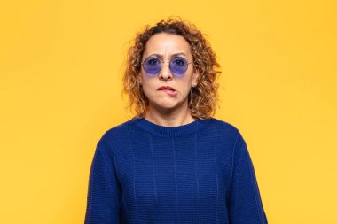 İspanyol orta yaşlı kadın şaşkın ve şaşkın görünüyor. Sinirli bir hareketle dudağını ısırıyor. Sorunun cevabını bilmiyor.