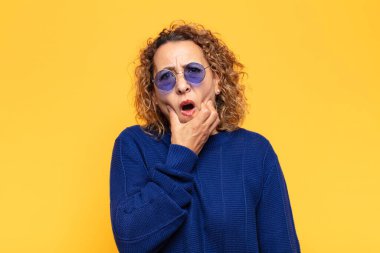 İspanyol orta yaşlı kadın ağzı ve gözleri sonuna kadar açık ve eli çenesinde, hoş olmayan bir şok geçiriyor, ne ya da vay canına diyor.