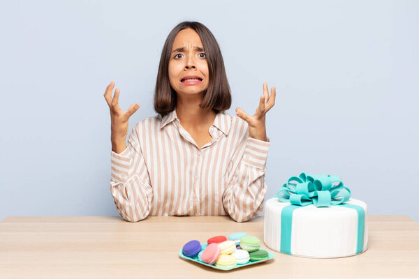hispanic woman screaming with hands up in the air, feeling furious, frustrated, stressed and upset