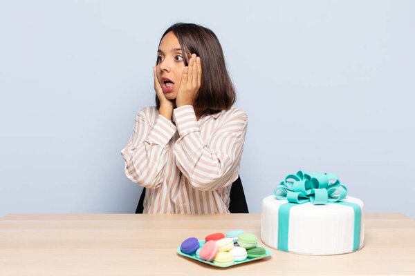 hispanic woman feeling happy, excited and surprised, looking to the side with both hands on face
