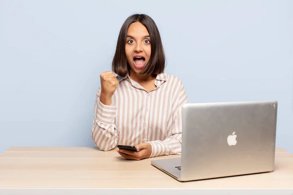 stock image hispanic woman feeling shocked, excited and happy, laughing and celebrating success, saying wow!