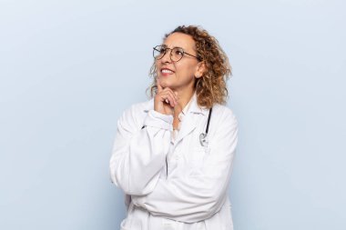 İspanyol orta yaşlı kadın mutlu bir şekilde gülümsüyor ve hayal kuruyor ya da şüphe ediyor.