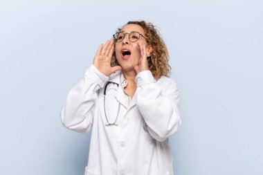 İspanyol orta yaşlı kadın mutlu, heyecanlı ve pozitif hissediyor. Elleri ağızda, bağırıyor.