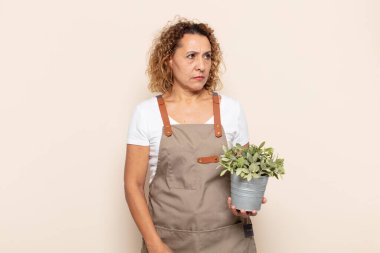 Hispanik orta yaşlı kadın üzgün, üzgün ya da kızgın hissediyor ve olumsuz bir tutumla yan yana bakıyor, anlaşmazlık içinde kaşlarını çatıyor