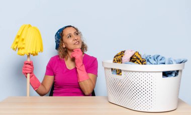 İspanyol orta yaşlı kadın mutlu, kendinden emin bir ifadeyle gülümsüyor elleri çenesinde, merak ediyor ve yan tarafa bakıyor.