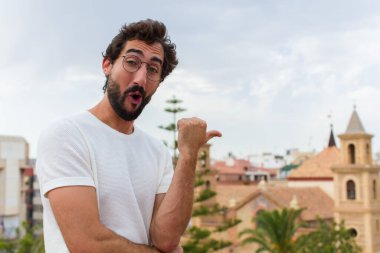 Genç sakallı adam dışarıda poz veriyor.