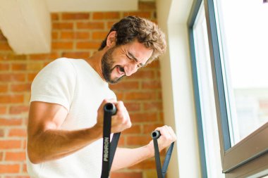 Genç sakallı adam evde egzersiz yapıyor.