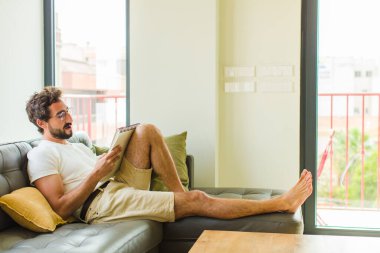 Genç adam evde kitap okuyor.