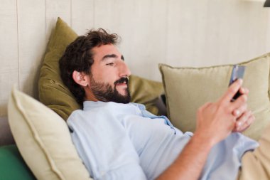 Genç sakallı adam evde dinleniyor.