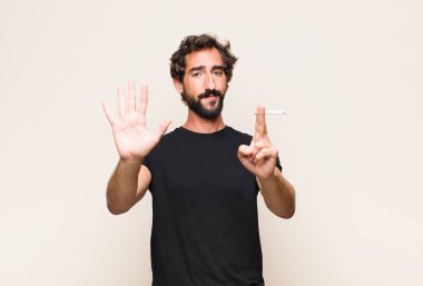 Genç sakallı adam sigara içiyor.