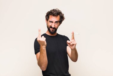 Genç sakallı adam sigara içiyor.