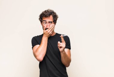 Genç sakallı adam sigara içiyor.