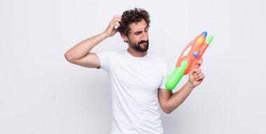 Su tabancası olan genç bir adam.