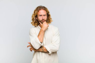 Sarışın adam düşünüyor, kuşkulu ve şaşkın hissediyor, farklı seçenekleri var, hangi kararı vereceğini merak ediyor.