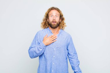 Sarışın adam şaşkın, şaşkın ve şaşırmış hissediyor, elleri göğsünde ve ağzı açık, kim olduğunu söylüyor, ben mi??