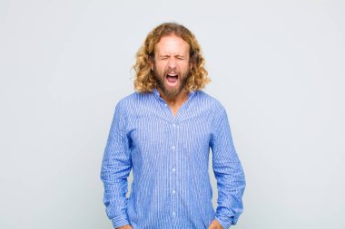 Sarışın adam korkmuş ve şok olmuş hissediyor, ağzı açık şaşkınlık içinde.