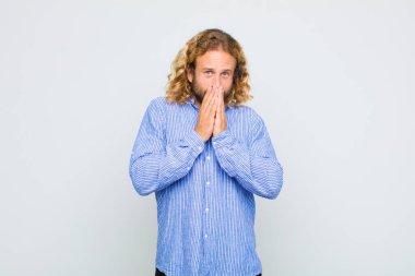 Sarışın adam mutlu ve heyecanlı, şaşırmış ve şaşırmış elleri ağızda, tatlı bir ifadeyle kıkırdıyor.