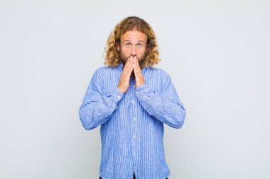 Sarışın adam endişeli, üzgün ve korkmuş hissediyor, elleriyle ağzını kapatıyor, endişeli ve berbat görünüyor.