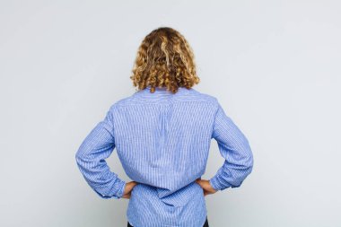 Sarışın bir adam kafası karışık mı yoksa şüphe ve soru dolu mu? Elleri kalçasında, dikiz aynasından merak ediyor.